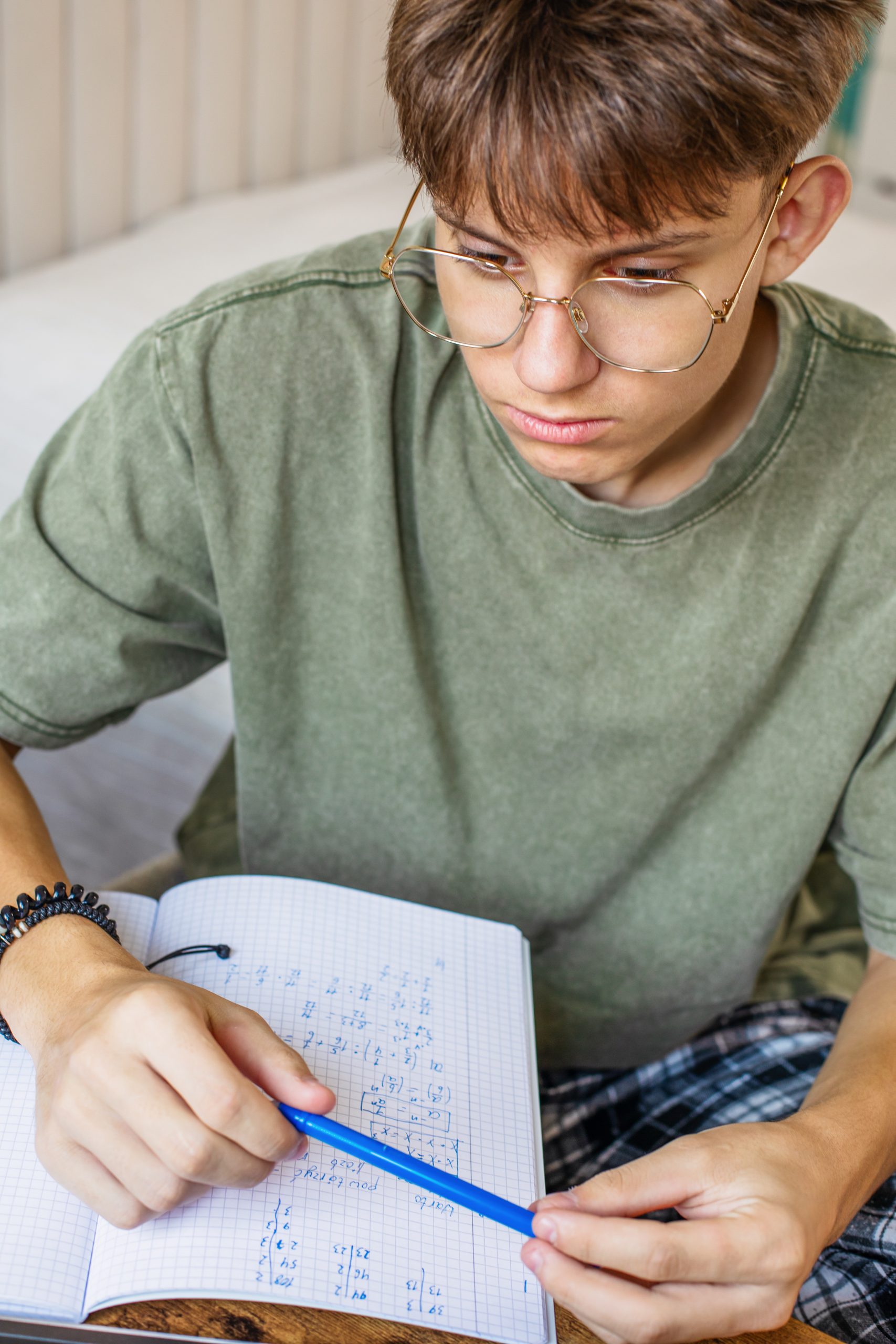 High school student with glasses studying handwritten algebra equations in a notebook during Algebra I tutoring with Tutor of Dragons in Southlake, Texas