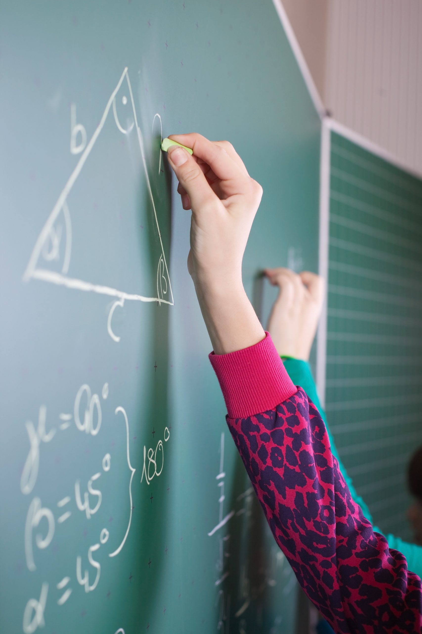 Student drawing a labeled triangle with angle measurements on a chalkboard during Geometry tutoring with Tutor of Dragons in Southlake, Texas